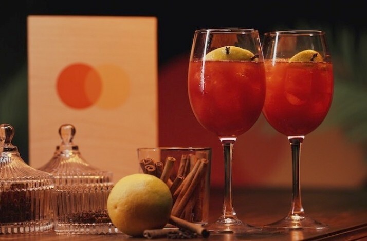 Two glasses of Mediterranean Sangria garnished with cinnamon with the Mastercard logo visible in the background.